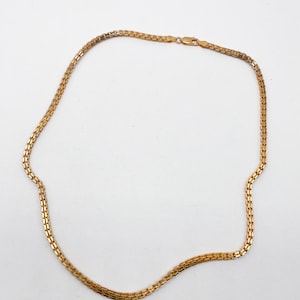 Pu&ograve; includere: Una collana a catena d'oro con un design a catena a scatola.