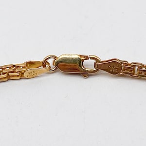 Pu&ograve; includere: Primo piano di una chiusura di collana a catena d'oro con l'iscrizione "925 ITALY" su un lato e "925" sull'altro.