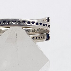 May include: Close-up of a silver ring with a heart design. The ring is marked with "S925 ALE".