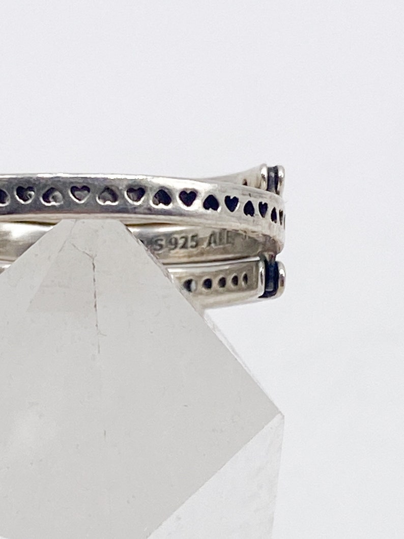 May include: Close-up of a silver ring with a heart design. The ring is marked with "S925 ALE".