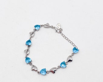 May include: A silver bracelet with a delicate chain and heart-shaped links. Each link is adorned with a light blue gemstone.