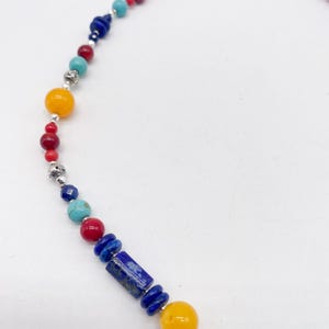 Pu&ograve; includere: Una collana di perline colorate con perline blu, rosse, gialle e turchesi. La collana &egrave; realizzata con accenti in metallo argentato e una chiusura.