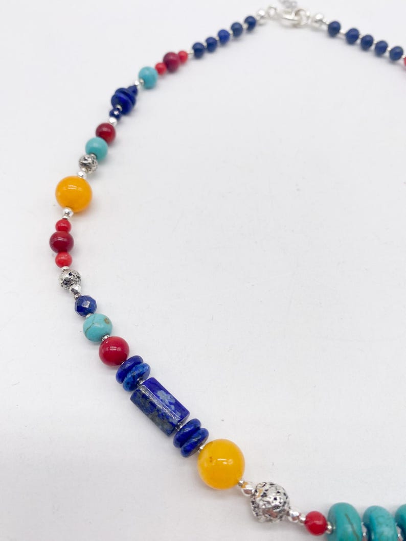 Pu&ograve; includere: Una collana di perline colorate con perline blu, rosse, gialle e turchesi. La collana &egrave; realizzata con accenti in metallo argentato e una chiusura.