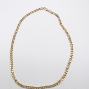 May include: A gold chain necklace with a curb link style. The chain is about 18 inches long.