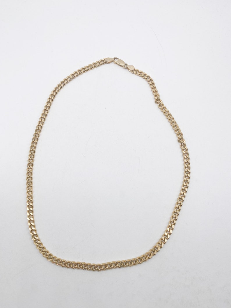 May include: A gold chain necklace with a curb link style. The chain is about 18 inches long.