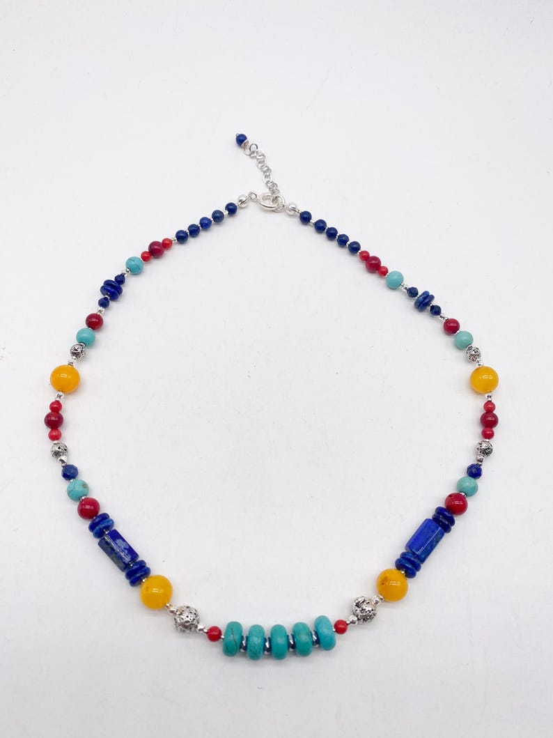 Pu&ograve; includere: Una collana di perline colorate con perline blu, rosse, gialle e turchesi. La collana ha una chiusura argentata.