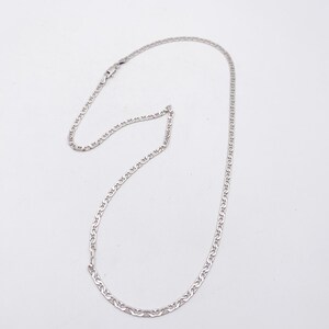 May include: A silver-colored chain necklace with a delicate, linked design. The necklace is displayed against a plain white background, highlighting its simple elegance. The chain is likely made of a precious metal.