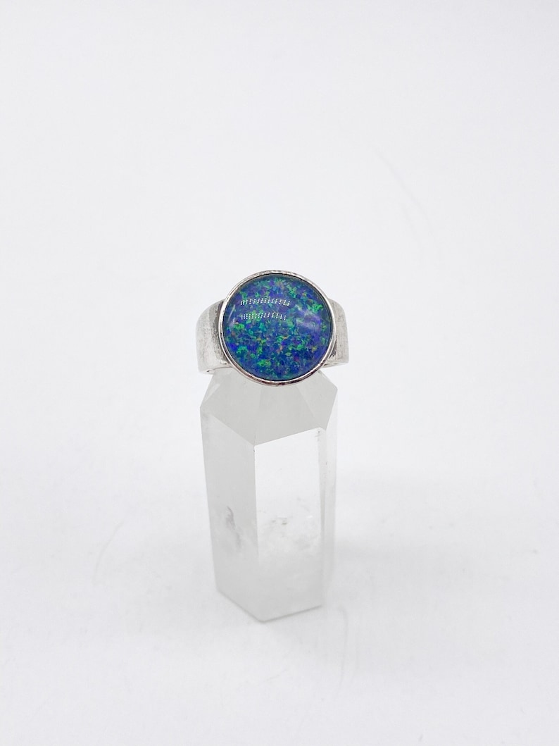 May include: A silver ring with a blue and green opal gemstone set in a bezel setting.