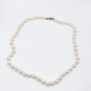 May include: A delicate necklace composed of numerous round, off-white pearls. The pearls are strung together, forming a continuous strand that fastens with a small, silver-toned clasp. The necklace is displayed against a plain white background.