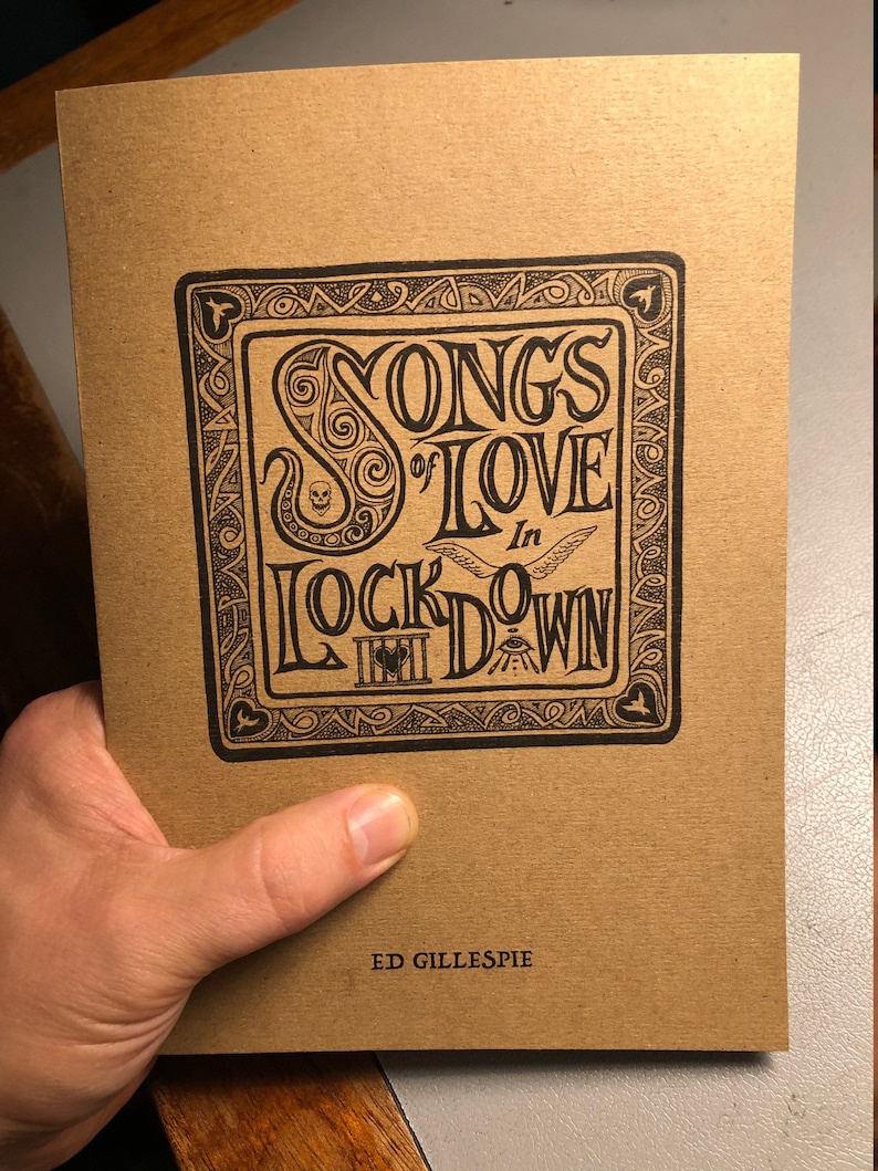 May include: A brown paper book cover with a black and white illustration of a title that reads "Songs of Love in Lockdown" with a decorative border. The author's name, "Ed Gillespie", is printed in black at the bottom of the cover.