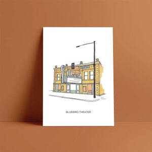 May include: A hand-drawn illustration of the Bluebird Theater in Denver, Colorado. The building is yellow with a blue and white sign that reads "Bluebird" and a red sign that reads "Colfax".