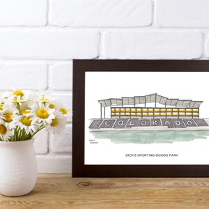 K&ouml;nnte beinhalten: Eine Schwarzwei&szlig;illustration eines Stadions mit dem Text "COLORADO" und "DICK'S SPORTING GOODS PARK" darunter. Das Stadion hat ein graues Dach und gelbe Fenster.