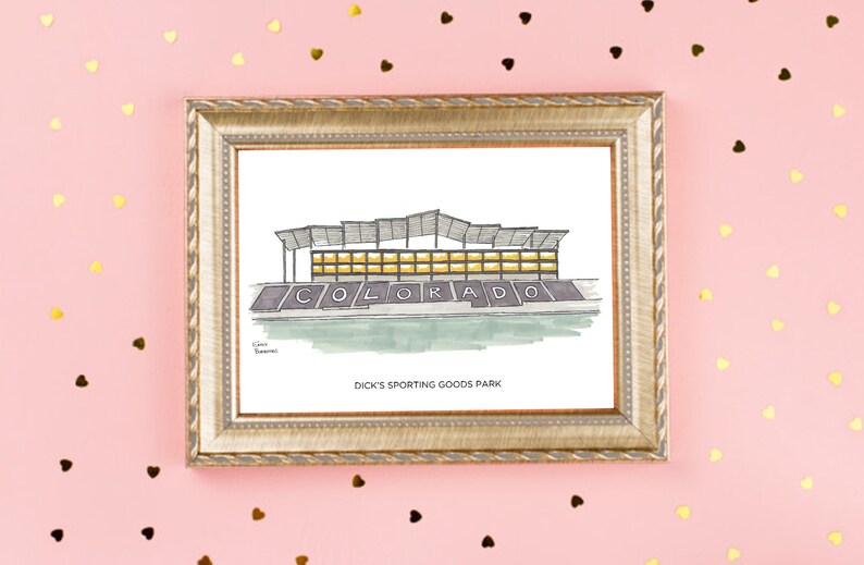 K&ouml;nnte beinhalten: Eine gerahmte Illustration eines Stadions mit dem Wort "COLORADO" in gro&szlig;en Buchstaben auf der Vorderseite. Der Text unter dem Stadion lautet "DICK'S SPORTING GOODS PARK".