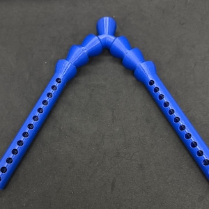 Könnte beinhalten: Zwei leuchtend blaue, flexible Kunststoffschläuche, die an einem zentralen Punkt verbunden sind und ein V bilden. Jeder Schlauch hat eine Reihe von gleichmäßig verteilten Löchern. Die Schläuche sind für den Flüssigkeitstransport konzipiert.