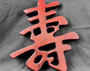 Madera maciza con acabado de caoba. Carácter chino Shou que significa larga vida o longevidad.