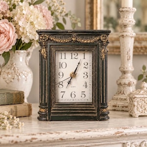 May include: A rectangular mantel clock with a distressed black finish and gold-toned decorative molding. The clock face is white with black Arabic numerals and black hands. The word QUARTZ is printed in small black letters below the center hands.