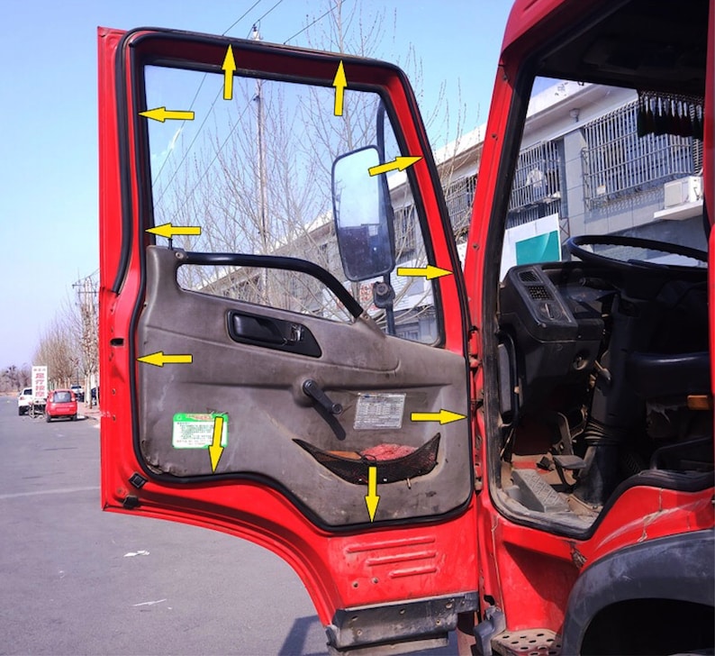 May include: A red truck door with a black rubber seal around the window. The door is open and the interior of the truck is visible. The door has a black handle and a black latch. The window is made of clear glass and has a black frame.