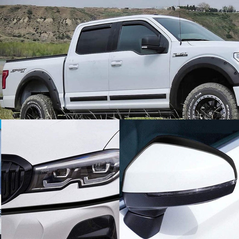 May include: A white pickup truck with black accents and a "Sport" decal on the side. The truck has black wheels with all-terrain tires. The truck is parked on a grassy area with a hill in the background.