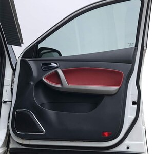 May include: A white car door with a black interior panel and a red leather door handle. The door is open and the window is rolled down.