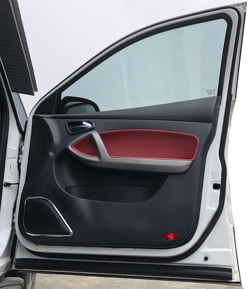May include: A white car door with a black interior panel and a red leather door handle. The door is open and the window is rolled down.