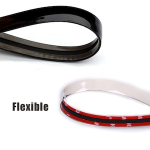 May include: A close-up of a flexible, black and silver trim strip with adhesive backing. The trim strip is designed to be used on car interiors or exteriors.