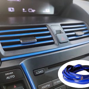 May include: Blue car interior trim molding with a roll of the trim in the lower right corner. The trim is blue and black and has a glossy finish.