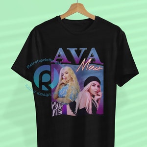Könnte beinhalten: Schwarzes T-Shirt mit einem Grafikdruck von Ava Max. Die Grafik hat ein Retro-Design mit einem rosa-blauen Farbschema. Der Text "Ava Max" ist in einer fetten, bunten Schrift gedruckt.