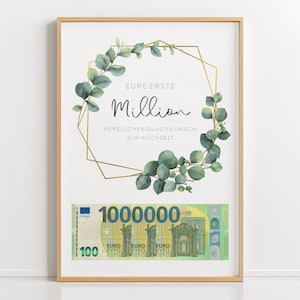 Puede incluir: Una impresión enmarcada con un marco geométrico dorado y una corona de eucalipto. La impresión dice "EURE ERSTE Million HERZLICHEN GLUCKWUNSCH ZUR HOCHZEIT" y presenta un billete de 1.000.000 euros.