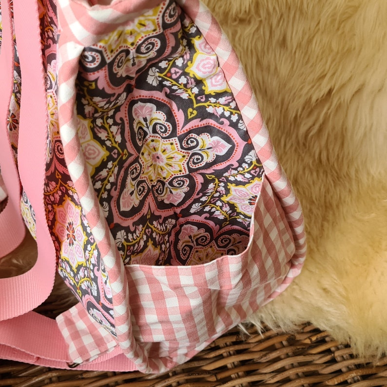 Puede incluir: Bolso tote de tela a cuadros rosas y blancos con una correa rosa. El interior del bolso presenta un estampado floral de cachemira en rosa, negro, amarillo y blanco.