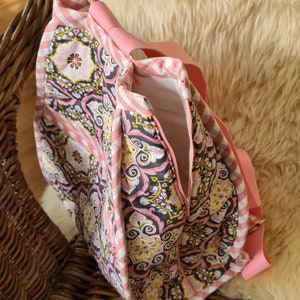 Puede incluir: Un bolso tote estampado en rosa y blanco con cierre de cremallera. El bolso presenta un dise&ntilde;o floral y de cachemira en rosa, negro y amarillo. Las correas y el ribete son de color rosa liso.