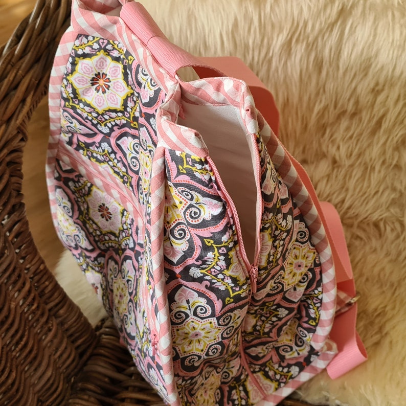 Puede incluir: Un bolso tote estampado en rosa y blanco con cierre de cremallera. El bolso presenta un dise&ntilde;o floral y de cachemira en rosa, negro y amarillo. Las correas y el ribete son de color rosa liso.