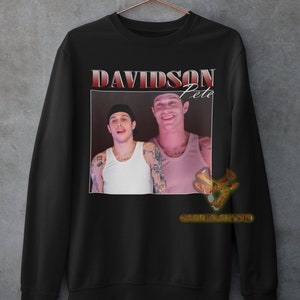 May include: Black sweatshirt with a red graphic print of Pete Davidson. The graphic features a photo of Davidson with the text "Davidson Pete" above the photo.
