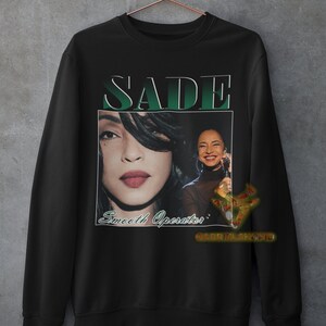 May include: Black sweatshirt with a vintage-style graphic of Sade, a singer, with the text "SADE" and "Smooth Operator" printed on the front.
