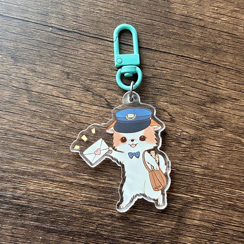 May include: A clear acrylic keyring featuring a cartoon dog dressed as a mail carrier. The dog wears a blue hat and bow tie, holding a letter with a heart. It has a brown satchel and a teal clasp.