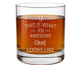 May include: A clear glass tumbler filled with amber liquid, featuring an upward-pointing arrow and the etched white text: THIS IS WHAT AN AWESOME Chef LOOKS LIKE. The glass has a thick base and smooth, transparent walls showcasing the beverage inside.