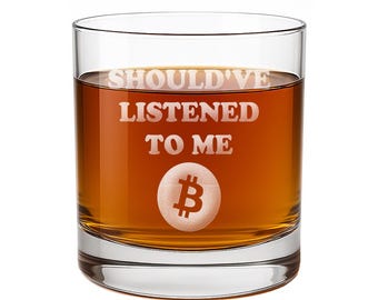 May include: A clear glass tumbler filled with an amber-colored liquid. The front of the glass features the etched white text SHOULD'VE LISTENED TO ME positioned above a circular Bitcoin symbol icon, creating a distinct contrast against the liquid.