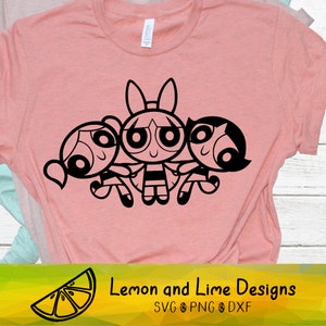 May include: Black and white line art illustration of the Powerpuff Girls, Blossom, Bubbles, and Buttercup, standing together. The image is on a pink t-shirt.
