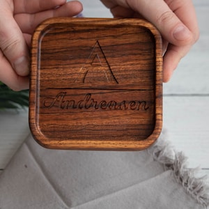 May include: A wooden coaster with a triangular design and the name "Andreasen" engraved on it.