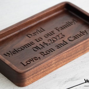 May include: A wooden tray with a personalized message engraved on the surface. The message reads "David Welcome to our Family 01.14.2023 Love, Ron and Candy".