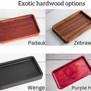 May include: Four wooden trays in different colors and wood types: Padauk, Zebrawood, Wenge, and Purple Heart. The trays are all rectangular and have a slightly raised edge. The text "Words can't espresso how much I love you" is engraved on the Padauk tray. The text "Taury" is engraved on the Zebrawood tray. The text "TRE" is engraved on the Wenge tray.