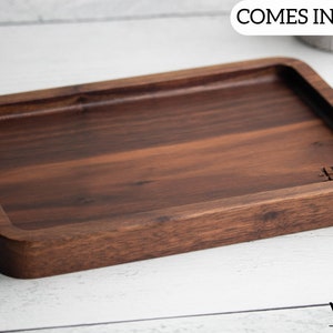 Könnte beinhalten: Ein rechteckiges Holztablett mit einer dunkelbraunen Oberfläche. Das Tablett hat einen erhöhten Rand und eine glatte Oberfläche. Das Tablett ist aus Walnussholz gefertigt und mit "#1" gekennzeichnet.