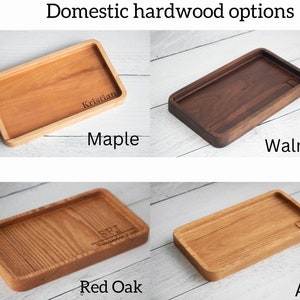 May include: Four wooden trays made of different types of wood: maple, walnut, red oak, and ash. Each tray has a slightly different grain pattern and color. The trays are all rectangular and have a raised edge.