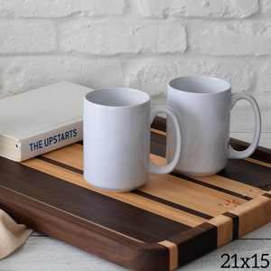 Op de afbeelding: Twee witte keramische mokken op een houten serveerschaal met een gestreept ontwerp. De schaal is gemaakt van walnoot- en esdoornhout en meet 53,3 x 38,1 cm. De schaal is ook gegraveerd met de woorden "The Wooden Tray".