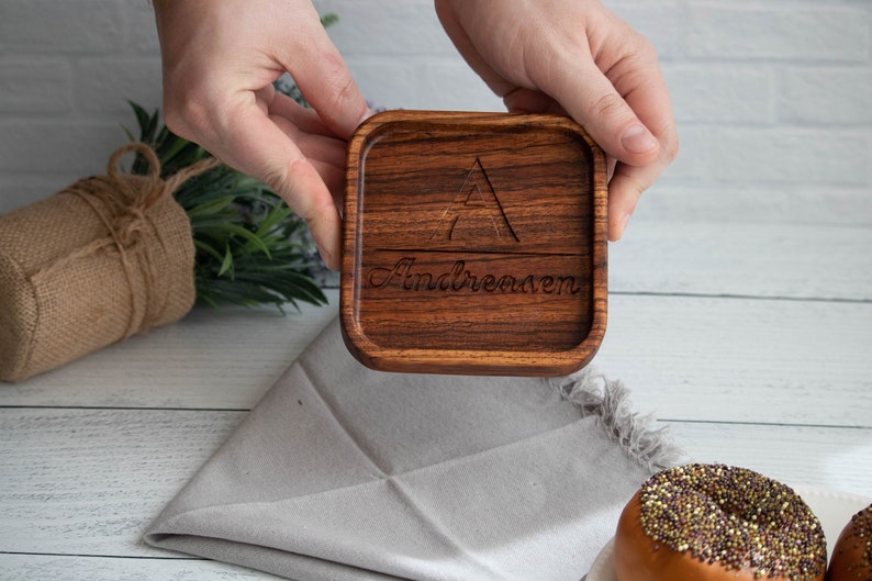 May include: A square wooden coaster with a triangle design and the name "Andreason" engraved on it.