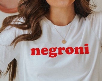 May include: White t-shirt with the word "negroni" printed in red letters.
