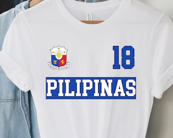 May include: White t-shirt with a blue and white Philippine coat of arms, the text "PILIPINAS" in blue with a white outline, and the number "18" in blue.
