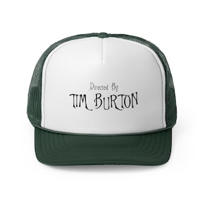 May include: White trucker hat with a green mesh back. The front of the hat has black text that reads "Directed By TIM BURTON".