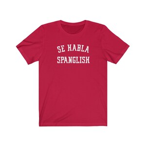 May include: Red short-sleeved t-shirt with white text that reads "Se Habla Spanglish".