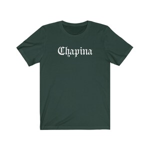 May include: A dark green t-shirt with the word "Chapina" printed in white on the front in a gothic font.