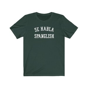 May include: A dark green t-shirt with the text "SE HABLA SPANGLISH" printed in white.